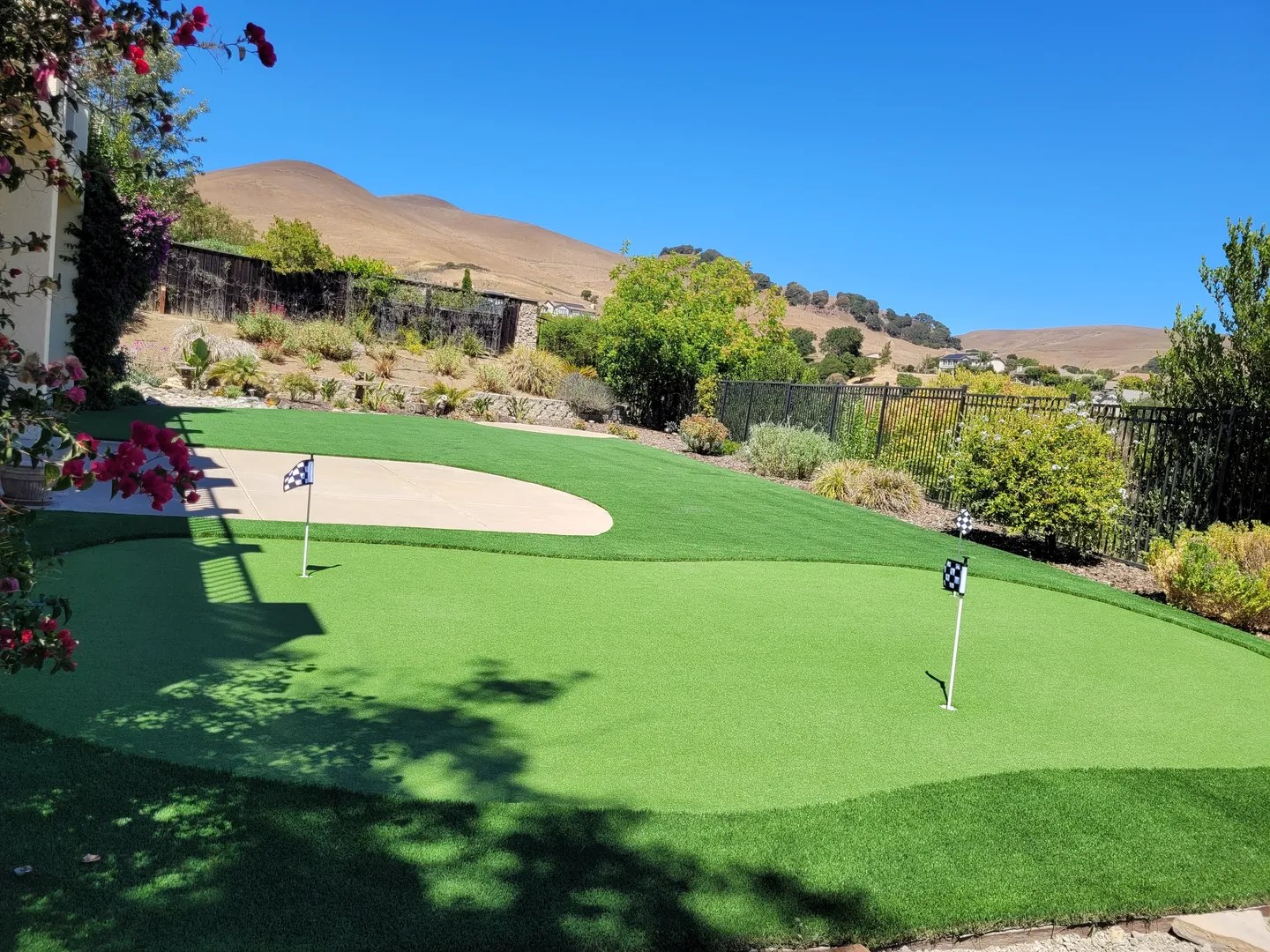 A golf course with a green and sand trap.